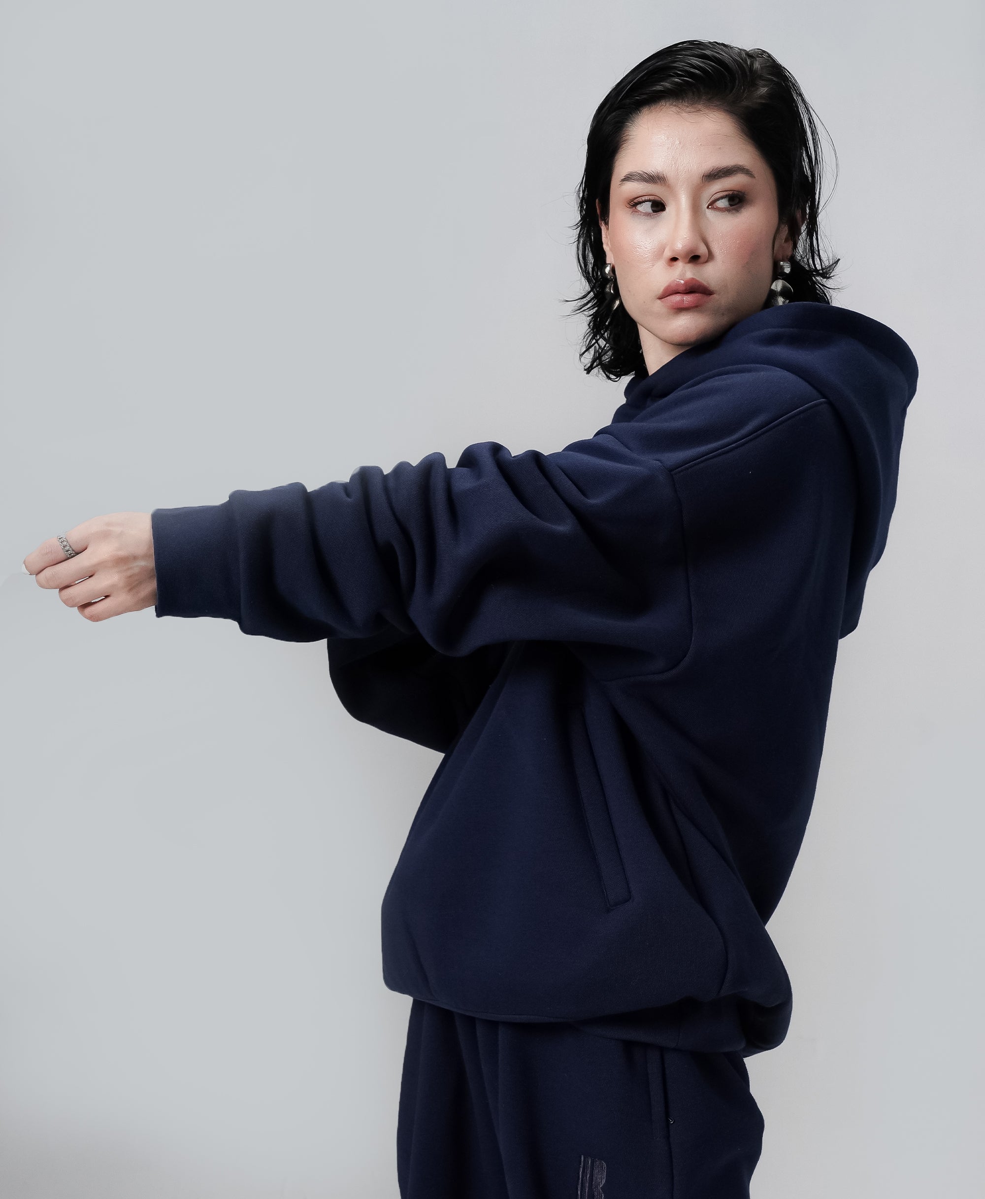 Person wearing a navy blue hoodie and pants against a plain background